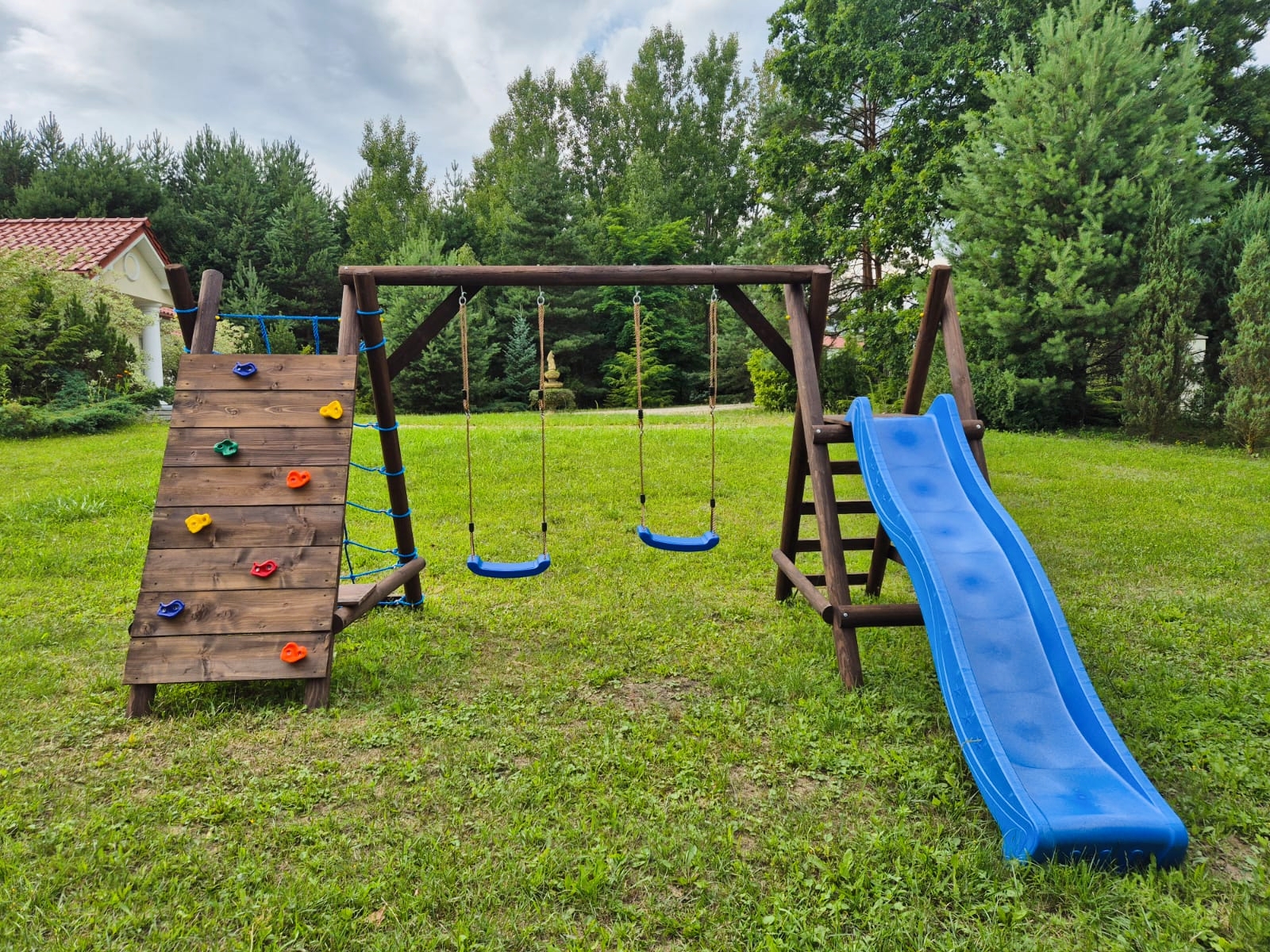 Drewniany plac zabaw z huśtawkami, ścianką wspinaczkową i zjeżdżalnią w ogrodzie, atrakcje dla dzieci w agroturystyce Stara Dawna Chata Polska