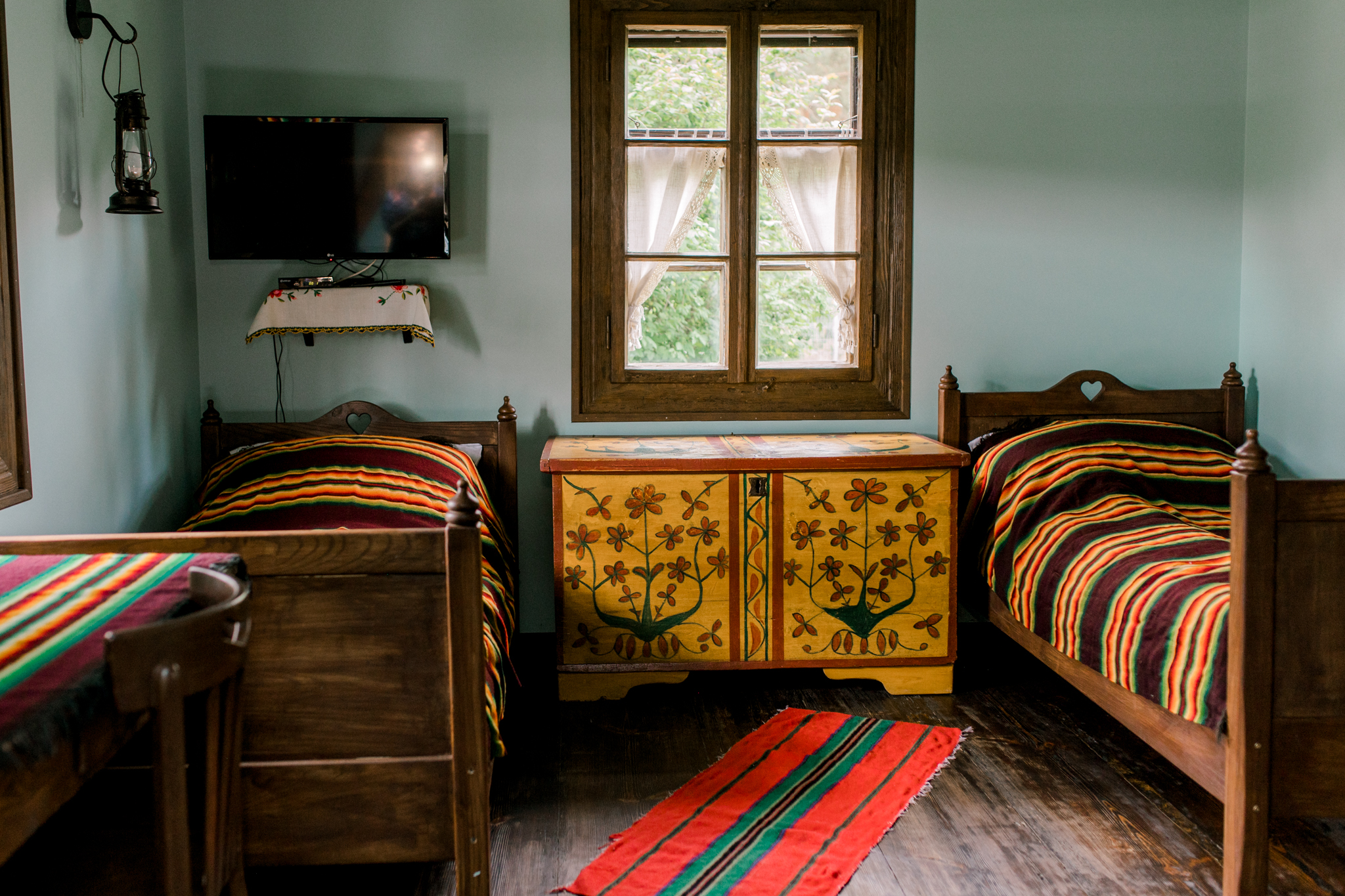 Dwupokojowe wnętrze domku agroturystycznego z dwoma łóżkami, TV i malowaną szafką, idealne na rodzinny wypoczynek