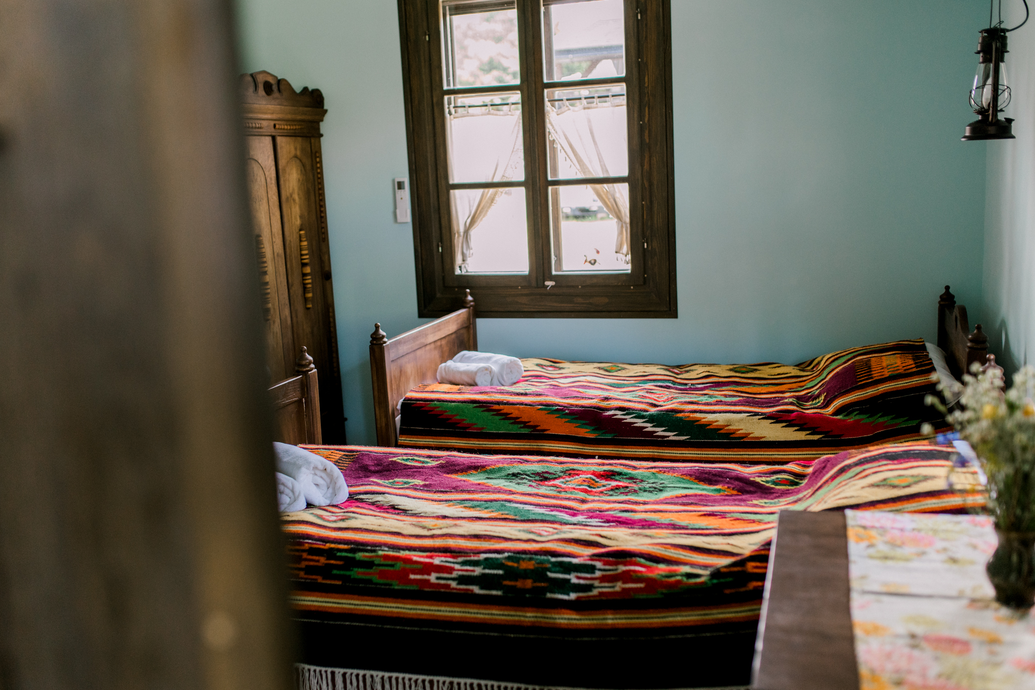 Przytulny pokój do wynajęcia w Starodawnej Chacie z dwoma łóżkami i ozdobnymi kocami — idealny do opisów noclegów, agroturystyki i stylowych wiejskich aranżacji wnętrz