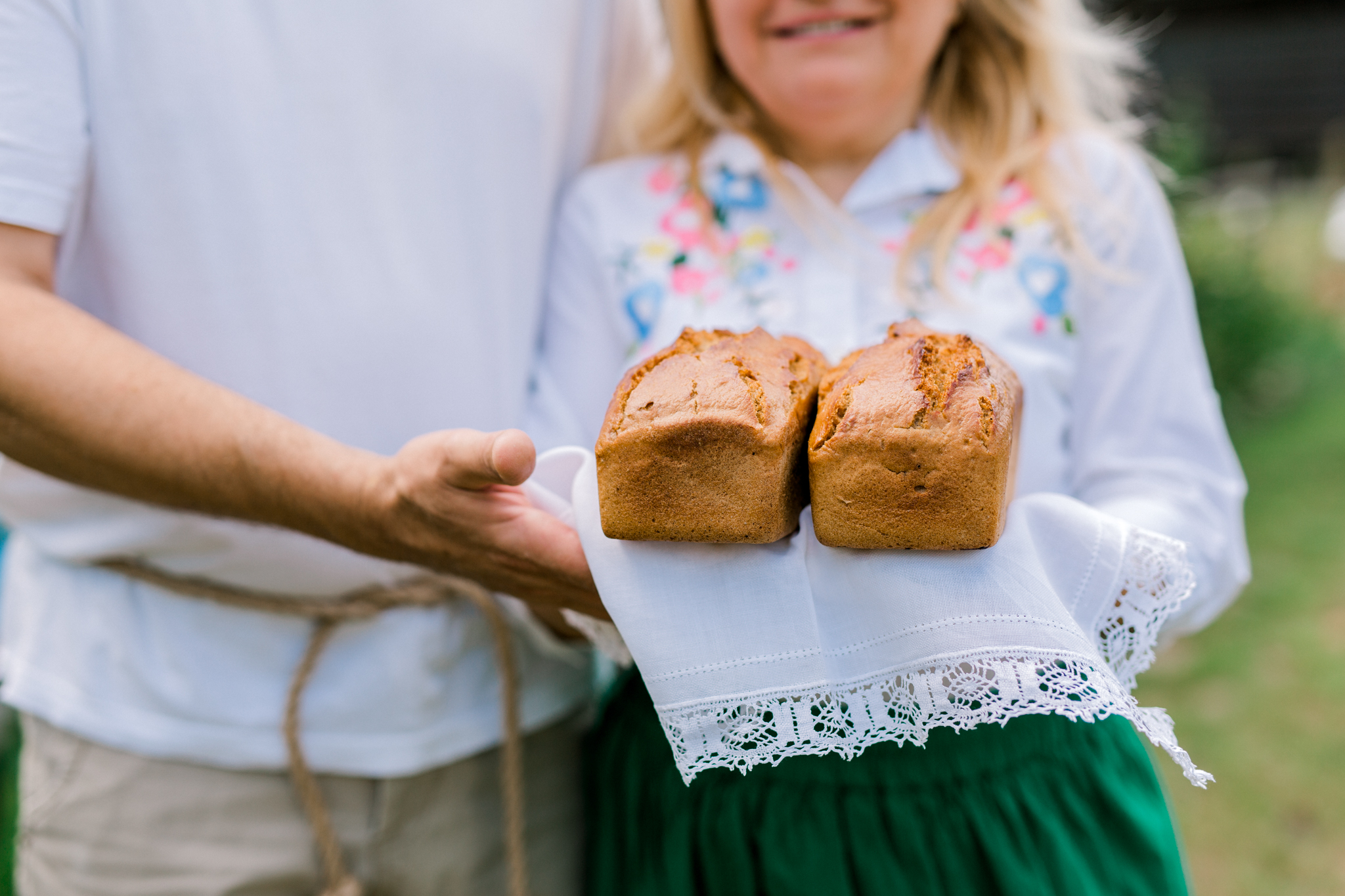 Tradycyjny polski chleb trzymany przez parę w folkowych strojach, agroturystyka Polska, wakacje na wsi