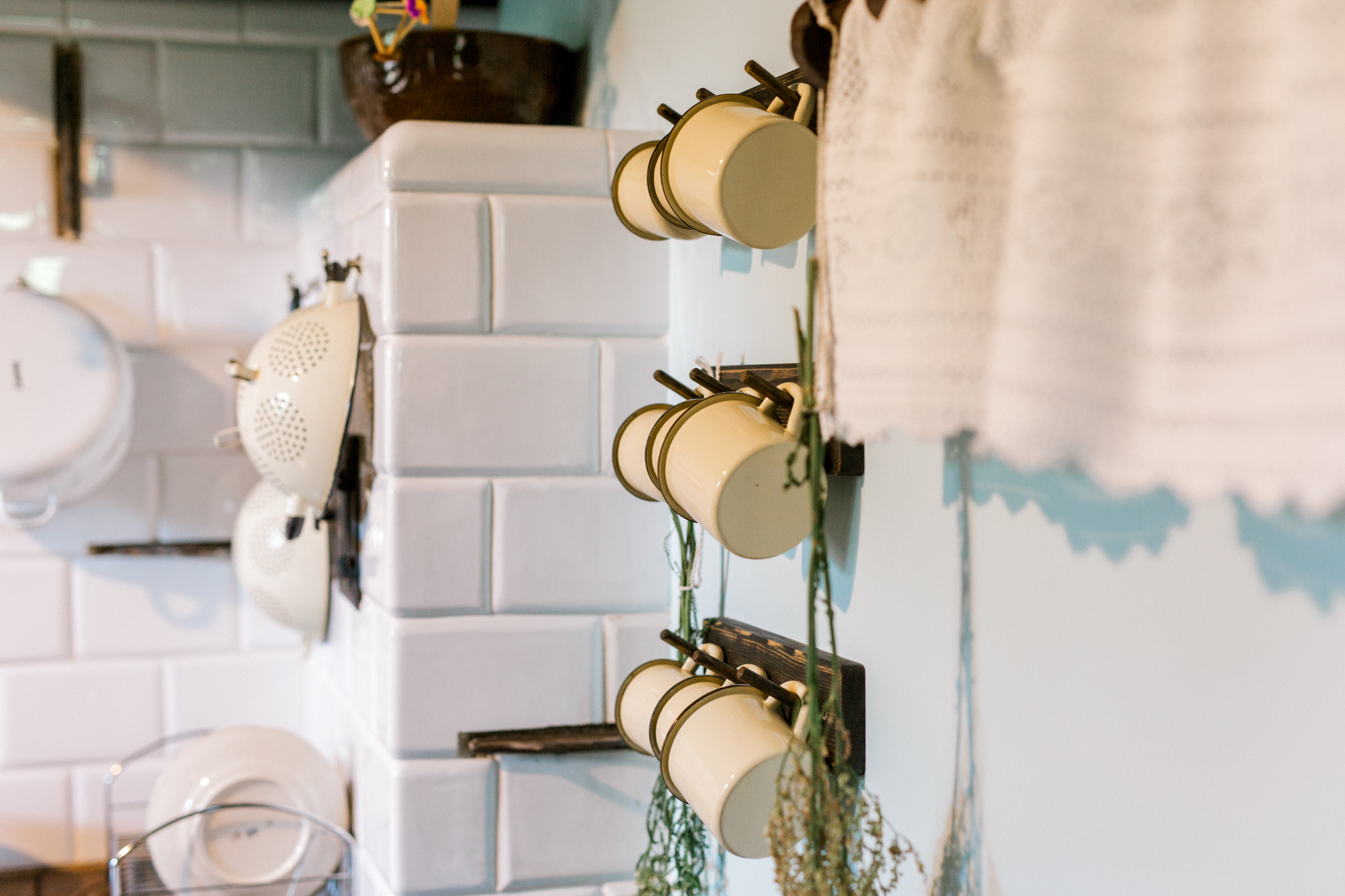 Wiszące naczynia kuchenne i suszone zioła na kafelkowej ścianie w rustykalnej kuchni, inspiracja do aranżacji domu w stylu vintage.