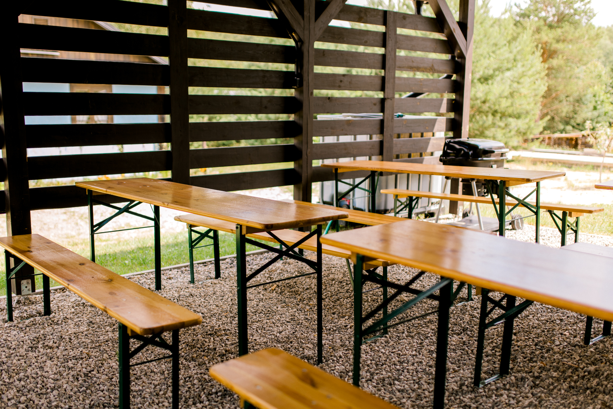 Drewniane stoły piknikowe pod zadaszeniem w ogrodzie, miejsce na grill w agroturystyce Polska