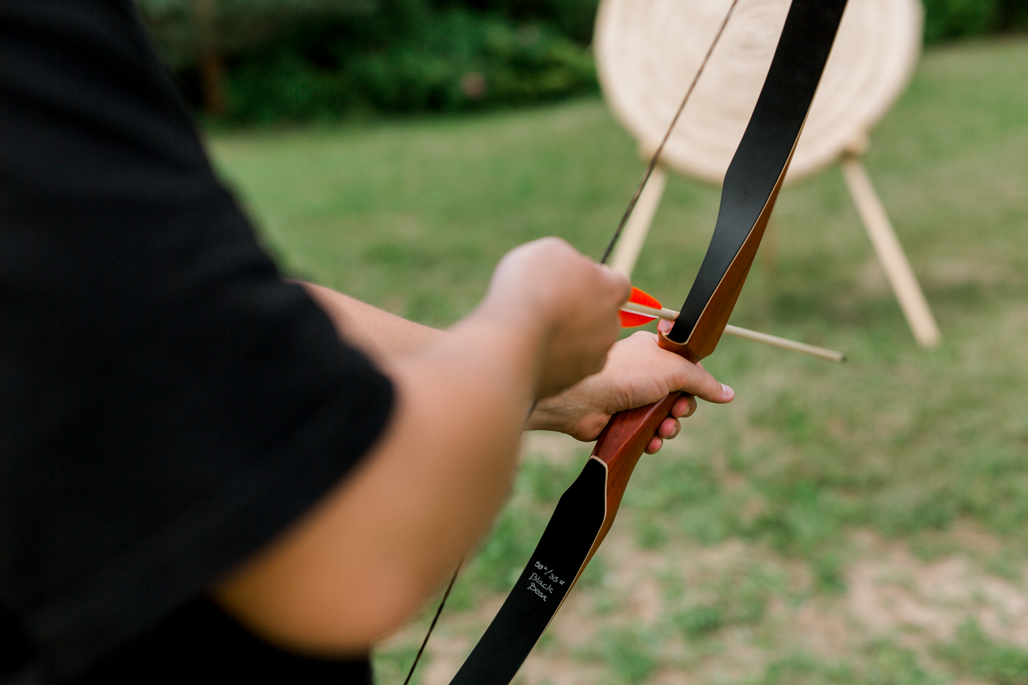 Osoba celująca z łuku w ogrodzie, atrakcje strzeleckie w agroturystyce, wakacje aktywne na wsi Polska